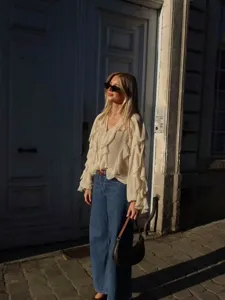 Outdoor lifestyle street style detail shot highlighting the V-neck layered ruffle blouse.