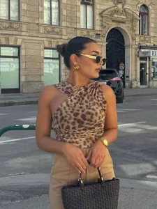 Detail view of stylish leopard print asymmetric mesh top worn in a chic urban street setting.