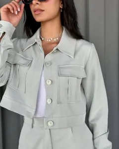 Gros plan détail de veste courte décontractée vert clair pour femme avec poches et boutons.