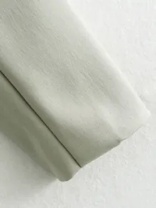 Gros plan détaillé de tissu de pantalon décontracté vert clair avec une fine texture sergée.