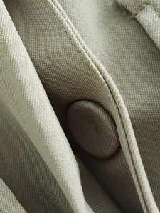 Gros plan détaillé sur la texture du tissu et le bouton élégant pour femme chic.