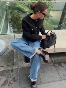 Elegant black round neck short tweed jacket paired with classic denim jeans for women.