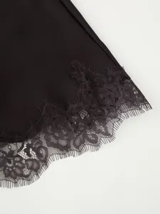 Close-up detail of women's black dress hem featuring elegant floral lace trim and satin fabric.