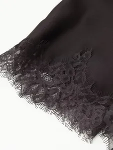 Close-up detail of black dress hem featuring elegant floral lace trim and smooth fabric texture.