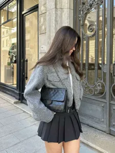 Detailed view of the women's grey tweed short jacket, featuring front zip and chic flap pockets.