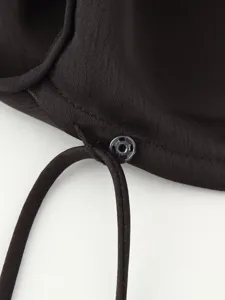 Close-up detail of dark dress fabric texture, adjustable drawstring and metallic snap.
