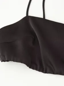 Close-up detail of dark strap top upper part featuring thin shoulder straps and smooth fabric.