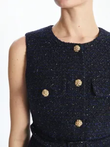 Close-up detail of women sleeveless tweed top with metallic gold woven buttons and texture.