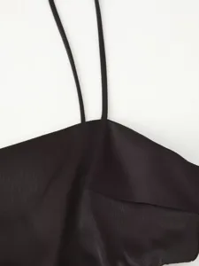 Close-up detail of women's elegant black slip dress featuring thin straps and straight neckline.