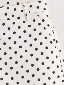 Vista detallada de pantalones de lunares con presilla de cinturón y diseño clásico.