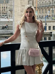 Outdoor detail view of a chic sleeveless mini dress featuring waist drawstring and bow accents.