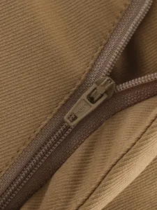 Close-up detail of brown corduroy garment zipper, showing fine craftsmanship and fabric texture.