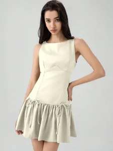 Detailed view of the beige sleeveless mini dress featuring cute bowknot ties and tiered skirt.