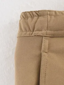 Khaki wide leg pants detail shot showing waist texture and fine stitching craftsmanship.