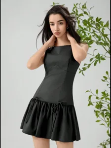 Detailed view of a chic black sleeveless mini dress featuring cute bow ties and drop-waist ruffle.