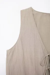 Close-up detail of women's textured sleeveless vest top in beige with tie front design.