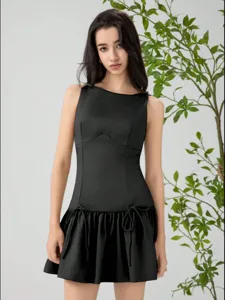 Detailed view of women's sleeveless black short dress featuring bow accents and ruffle hem.