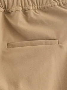 Detailed view of khaki casual trousers featuring elastic waistband and welt pocket design.