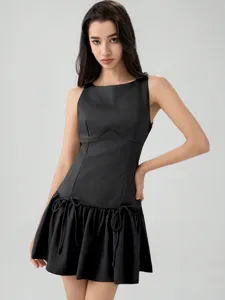 Sleeveless black mini dress detail, showcasing dropped waist bow tie and pleated hem design.