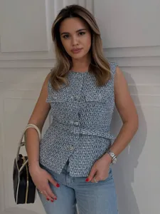 Detailed shot of a chic textured tweed sleeveless vest with metal buttons and matching belt.