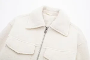 Textured fleece jacket detail closeup, cream white short coat with zipper and chest pockets.