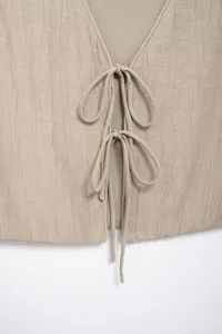 Beige textured vest detail with v-neck and double tie front, chic summer top design.