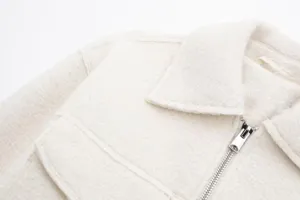 Close-up detail of women short bouclé jacket, textured fabric, metal zipper and lapel collar.