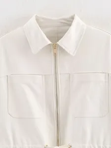 Close up detail of women off white utility jacket with collar, metal zipper and chest pockets.