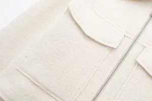 Close-up detail of textured tweed fabric jacket featuring metal zipper and pocket flap.