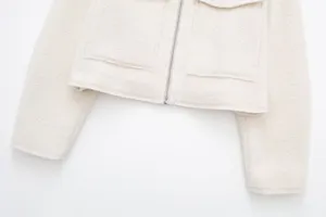 Close-up detail of women's short fleece jacket in cream white with front zipper pockets.