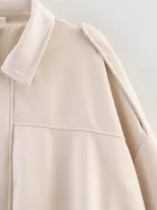Gros plan détail du col de veste en suédine beige, texture premium et coutures soignées.