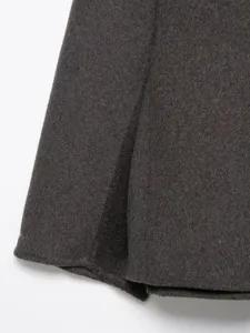 Close-up detail of dark grey woolen winter coat fabric, showing fine texture and stitching.