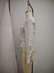 Side view detail of a classic black and white polka dot long sleeve blouse with belt.