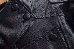 Détail de veste en cuir noir motif litchi pour femme, col à revers classique et boutons.