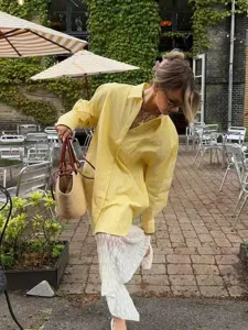 Outdoor lifestyle detail shot of a stylish yellow striped loose shirt paired with a lace skirt.