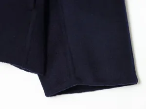 Close-up detail view of dark blue woolen fabric coat texture and smooth stitching.