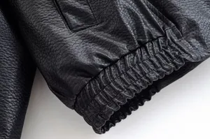 Gros plan détail de la manchette et de la texture en cuir noir à motif litchi élégant.