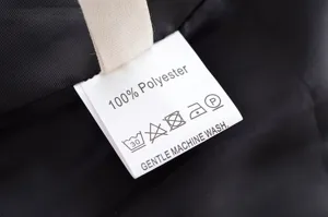 Vue detaillee de l etiquette d entretien de la veste noire montrant 100 pourcent de polyester.