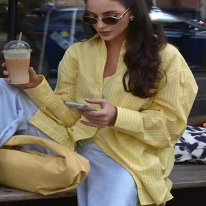 Detailed street style view of the striped loose casual shirt worn by a model outdoors.