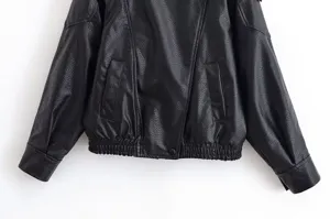 Veste en similicuir noir classique avec texture, coupe courte et poches élégantes.