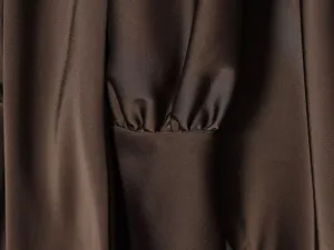 Close-up detail of smooth satin long sleeve cuff with delicate gathering on elegant dress.