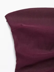 Detail view of stylish burgundy strapless top, asymmetric design with fine ruching texture.