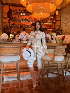 Detailed view of women's polka dot long sleeve shirt and high waist pants set in bar scene.