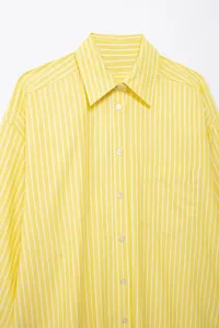 Detailed view of women's yellow and white striped loose casual shirt with classic collar.