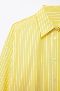 Detail shot of a women's yellow and white striped casual shirt collar and button placket.