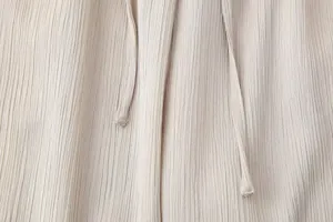 Vista cercana de la textura de tela arrugada ligera con detalle de cordón para ropa de mujer.
