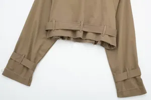Detailed shot of the cropped khaki trench coat featuring a stylish frayed hem and waist belt.