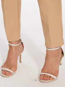 Detail shot of women's casual high-waisted suit trousers paired with elegant white heeled sandals.