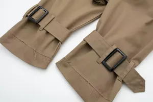 Detail shot of women's casual khaki trench coat cuff with black buckle and raw edge design.