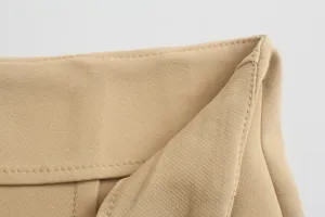 Closeup detail of khaki women's trousers waistband, showing neat fine stitching and fabric texture.
